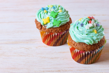 Colorful cupcakes on a white wooden background