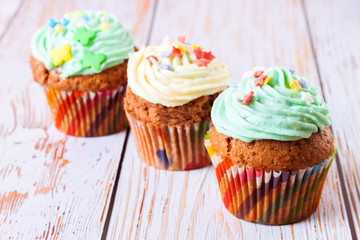 Colorful cupcakes on a white wooden background