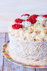 white cake with cream and red roses on white dish