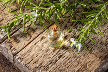 A bottle of essential oil with blooming rosemary twigs