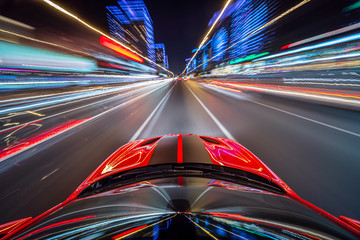 View from roof of the red muscle car Car moving in a night city, Blured road with lights with car on high speed. Concept rapid rhythm of a modern city.