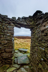 A scenic view from inside a stony mountain shelter in ruin under a grey stormy sky