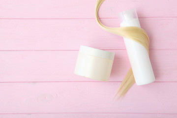 curl of blonde hair and hair care products on a colored background top view. Hair care concept.