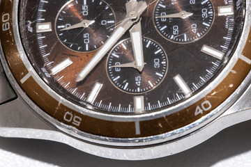 Close-up of a used wristwatch. The outer case is metallic and the inside is brown. Macro