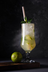 Refreshing lime cocktail with mint and ice on a dark background. Soft drink with lime and mint. Close-up.
