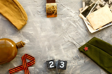 Flask, cap, soldier belt with a five-pointed star with a hammer and sickle and old photographs a wooden calendar  February 23 . Fatherland defender day.
