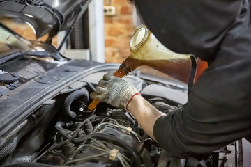 auto mechanic technician replacing and pouring motor oil into automobile engine at maintenance repair service station