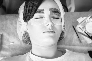 Beautician makes depilation of eyebrows with hot wax.