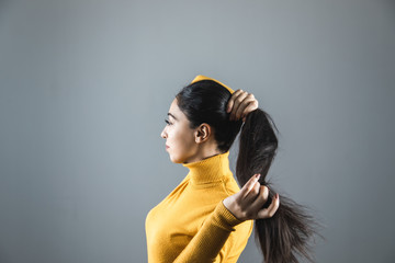 young woman tie the hair on grey background