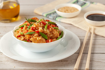 Tori chahan fried Japanese rice with vegetables and chicken in soy sauce in a black plate on a wooden table