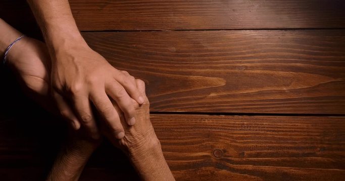 HELPING HAND. Detail of a Man's Hands Holding the Senior Woman Hands