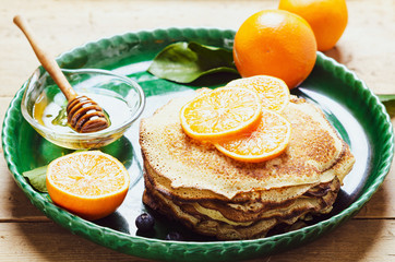 Stack of pancakes with blueberries and honey syrup.