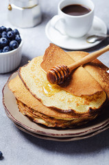 Stack of pancakes with blueberries and honey syrup.
