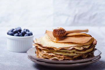 Stack of pancakes with blueberries and honey syrup.