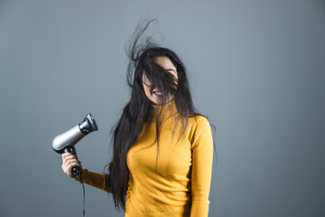young woman hand hairdryer on grey background