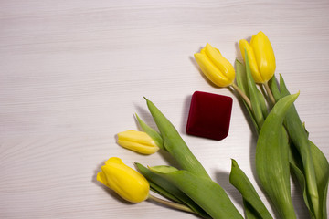 Flower tulip on white wooden background. Bouquet of the yellow tulip flowers. Valentines day concept, woman's day. Red gift box.