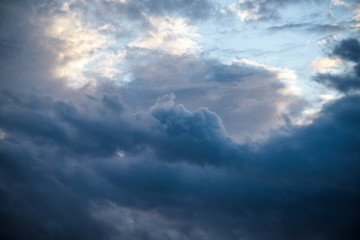 CLOSE UP: Dark grey stormy clouds gather above Lake Maggiore on a calm summer evening. Dramatic shot of clouds covering up the colorful sunlit morning sky. Orange hued evening sky and stormy clouds.