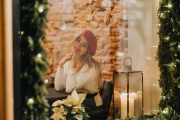 Fototapeta premium A beautiful young woman seen through the site of a festively decorated restaurant.