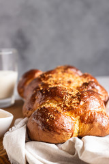 Homemade challah bread on a wooden cutting board over light grey stone background. Shabbat, hebraism traditional bread.