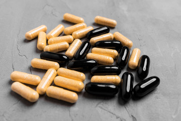 Black and yellow capsule pills on a gray background, antiviral.