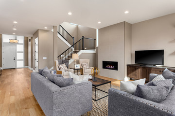 Beautiful living room interior in new home. Features fireplace with fire, built in shelving and cabinets, hardwood floors, and open concept design.