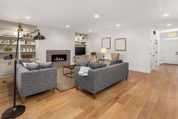 Beautiful living room in new home. Features fireplace with roaring fire, built in shelving and cabinets, hardwood floors, and open concept design.