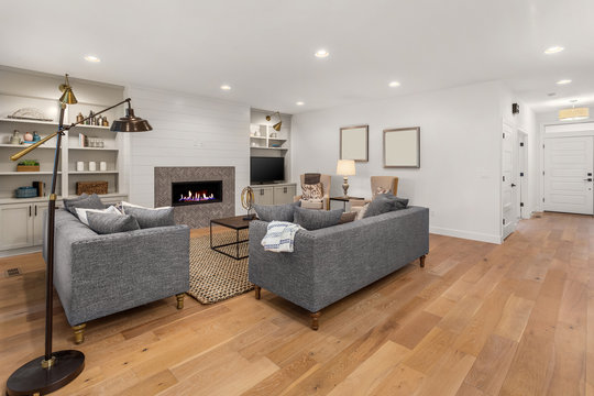Beautiful living room in new home. Features fireplace with roaring fire, built in shelving and cabinets, hardwood floors, and open concept design.