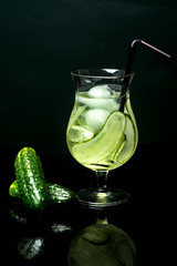 Glass of fresh cucumber juice on black background