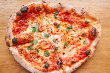 Pizza Margarita. Baked tasty margherita pizza in Traditional wood oven in Neapolitan restaurant, Italy.