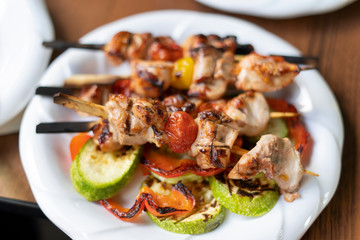 Skewers with kebab on a plate, fried chicken with cherry tomatoes.