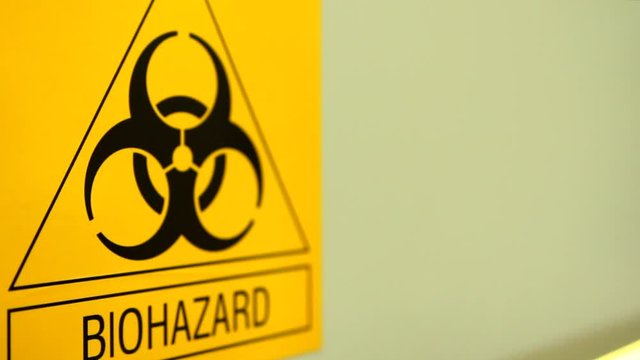 Biohazard sign on laboratory wall. Caution sign for authorised personnel. Yellow warning symbol of chemical contamination, toxic materials. Threat of unknown virus infection. Biological attack danger.