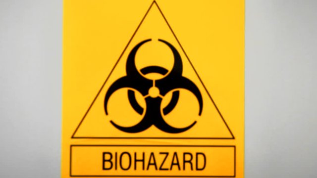 Biohazard sign on laboratory wall. Caution sign for authorised personnel. Yellow warning symbol of chemical contamination, toxic materials. Threat of unknown virus infection. Biological attack danger.