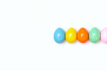 Top view of an Easter composition of painted eggs in bright juicy colors on a white background with a glossy texture. Holiday concept, flat layout, minimalism