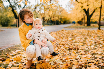 Young beautiful mother enjoys of spends time in the autumn park with her young child