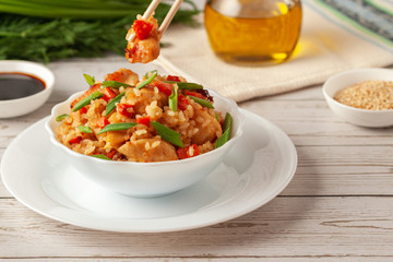 Tori chahan fried Japanese rice with vegetables and chicken in soy sauce in a black plate on a wooden table