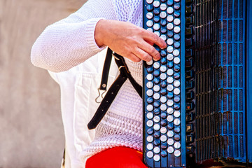 Closeup of sitting woman playing accordion, with focus on her hands and the keys featuring the...