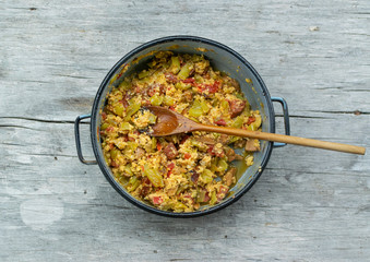 Vegetables, meat and mushroom fried in old pot on old wooden table