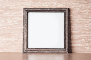 Square frame for photo on a light wooden background, place for text.