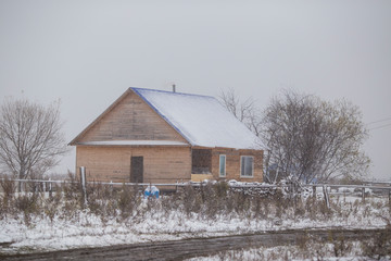 The village of Latin American Old Believers who returned to Russia in the Primorsky Territory. Wooden houses of Old Believers during a snowfall on a background of beautiful fields and mountains.