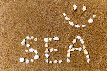 the inscription with stones in the sand the word "sea" and a smile