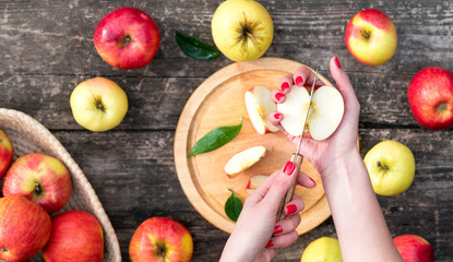woman cuts an apple on a wooden board. cooking food. top view