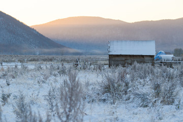 The village of Latin American Old Believers who returned to Russia in the Primorsky Territory. Wooden houses of Old Believers during a snowfall on a background of beautiful fields and mountains.