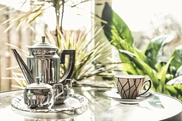 woman's hand holding hot teapot in morning sunlight, retro colors, a window through which the sun shines