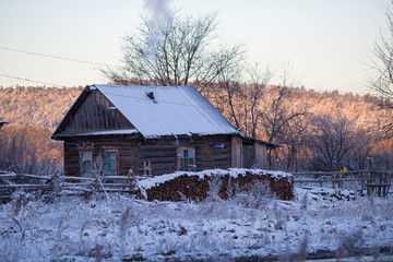 The village of Latin American Old Believers who returned to Russia in the Primorsky Territory. Wooden houses of Old Believers during a snowfall on a background of beautiful fields and mountains.