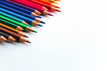 bright multi-colored flat lay pencils for drawing on a white background, place for text 