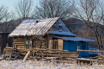 The village of Latin American Old Believers who returned to Russia in the Primorsky Territory. Wooden houses of Old Believers during a snowfall on a background of beautiful fields and mountains.