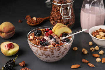 Granola crispy honey muesli with natural yogurt, fresh berries and fruit, chocolate and nuts in a glass bowl against a dark background, Healthy food, Closeup