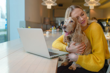 Happy smiling blonde woman hugging her lovely cocker spaniel puppy with eyes closed and joyful face...
