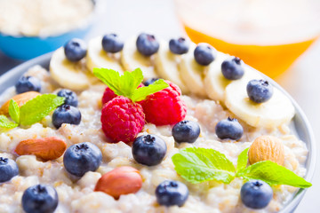 Healthy breakfast. Bowl of oatmeal porridge with fresh blueberries, raspberries, almonds and banana. Clean eating, dieting, detox, vegetarian food concept. Healthy concept