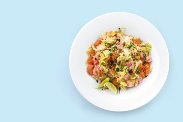 Healthy fresh salad with lettuce, greens, red caviar, shrimp, fillet salmon in plate isolated on blue background. Healthy food, clean eating, dieting, top view
